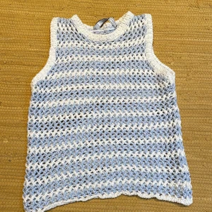 Randig stickad bomull top från Sportmax - Säljer en superfin stickad topp av bomull från Sportmax i vitt och ljusblått. Sportmax är en gren av MaxMara… en Italien märke Toppen är ärmlös med breda axelband och har ett luftigt, virkat mönster. Toppen är made  in Italy