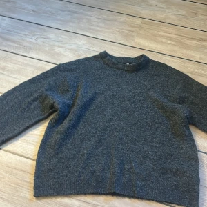 Mörkgrå stickad tröja från lager 157 - Mysig mörkgrå stickad tröja från lager 157 med rund halsringning och lång ärm. Enkel design som funkar till allt och är superbekväm att bära. Endast använd ett fåtal gånger