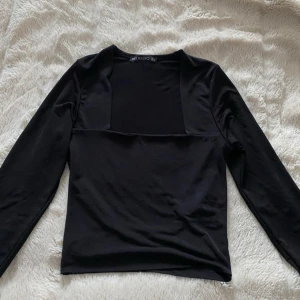 Svart långärmad topp från RADIO - Säljer en svart långärmad topp från RADIO med unik skärning över bröstet. Toppen har en stilren och enkel design som passar perfekt till jeans eller kjol. Mjuk och stretchig känsla, vilket gör den bekväm att bära hela dagen.