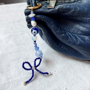 Handgjord bagcharm - Unik bagcharm med mixade pärlor i olika färger och former, dekorerat med en pärlad rosett  av små glaspärlor. Handgjord av mig! ✨