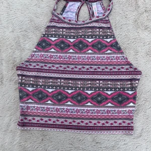 Mönstrad halterneck linne från FB Sister - Supersnygg halterneck linne från FB Sister i storlek S. Toppen har ett färgstarkt mönster i rosa, grått och vitt med blommiga och geometriska detaljer. Perfekt för varma dagar och ger en cool boho-vibe. Materialet är mjukt och stretchigt, vilket gör den riktigt bekväm.