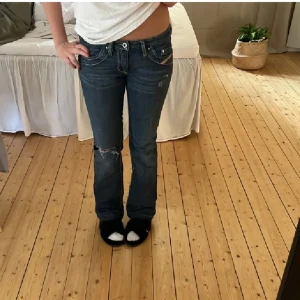 Diesel bootcut jeans med slitningar - Mörkblå jeans från Diesel med låg midja och bootcut passform. Snygga slitningar vid knäna och detaljerade nitar vid fickorna. Säljer dom nu för kommer inte till användning.💗