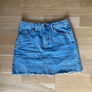 Blå jeanskjol från BDG  - Snygg blå jeanskjol från BDG med rå, fransig kant nertill och klassiska fickor både fram och bak. 