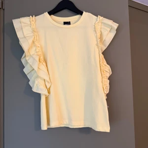 Gul volangtopp Gina Tricot - Supersöt ljusgul topp från Gina Tricot i bomull med volangärmar. Använda en gång 