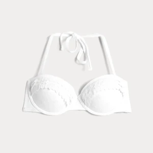 Vit bikiniöverdel med spetsdetaljer - Snygg vit bikiniöverdel med bygel, spetsdetaljer och broderade blommor. Den har knytband i nacken  som enkelt kan tas av och bäras som en bandeau bikini. Perfekt för en stilren look på stranden. Köpt på cubus för 249kr. Mycket bra skick endast använd en gång. Hör av dig vid frågor💞
