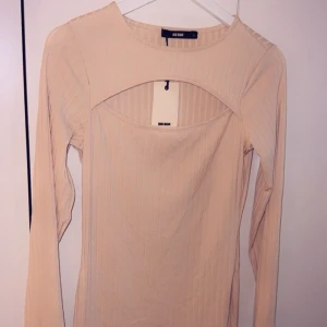 Klänning - Långärmad klänning från bikbok, aldrig använd, prislappen kvar! Slags ros/aprikos/beige färg.