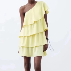 Gul volangklänning oneshoulder - Superfin ljusgul kortklänning med flera volanger och en axel. Klänningen har oneshoulder-design och är perfekt för sommarens alla tillfällen. Luftigt material och snygg passform som ger en lekfull och trendig look.💕 jättefin men tyvärr förstor för mig