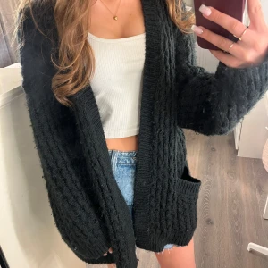 Svart stickad kofta från H&M - Lång supermysig stickad kofta från H&M i storlek M. I använt skick och nopprig men supermysig ändå!