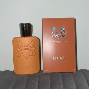 Parfums de Marly Althaïr - Exklusiv parfym från Parfums de Marly, Althaïr 125ml. Flaskan är matt orange med silverdetaljer och har ett elegant reliefmönster med två hästar och sköld. Kommer i matchande orange kartong med silvertext. Lyxig och modern design. 