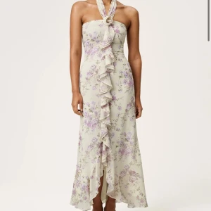 Adoore- lamia  halter neck dress  - Adoore klänning som är helt slutsåld i butik och hemsida. Superfin långklänning i ljus ton med lila och beige blommigt mönster. Klänningen har halterneck och volangdetalj framtill som ger en romantisk vibe. Sitter figurnära upptill och faller snyggt längs kroppen. Perfekt för sommarens alla tillfällen!