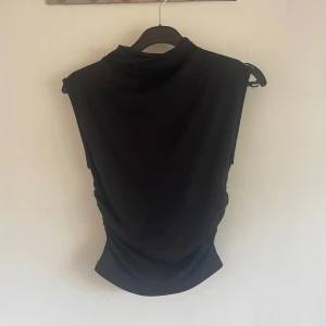 Svart croppad ärmlös topp - Säljer en svart, croppad ärmlös topp med hög hals. Knappt använd! 🫶