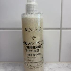 Revuele Shimmering Body Mist 200ml - Revuele Shimmering Body Mist med silvrig skimmer och lyxig doft. Sprayen kommer i en genomskinlig plastflaska med pump och innehåller 200 ml. Berikad med gurk- och kokosnötsextrakt för återfuktning och en glittrande finish på huden.