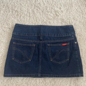 Mörkblå jeanskjol 💙 - Snygg mörkblå jeanskjol som jag tror är från äldre Vero Moda. De har snygga kontrastsömmar på bakfickorna och en cool knäppning vid midjan. Den har inga defekter, är perfekt till sneakers eller boots för en cool vardagslook. 💙