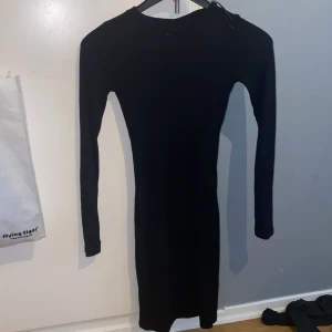 Svart tight klänning från Divided H&M - En svart, tight och ribbad klänning från Divided i storlek 34. Klänningen är kort, har lång ärm och rund halsringning. Perfekt för dig som gillar en enkel men stilren look. Den är figurnära och materialet är tunnt vilket är perfekt för sommaren :) vill ni ha bilder på är det bara att säga till 🫶🏻🫶🏻