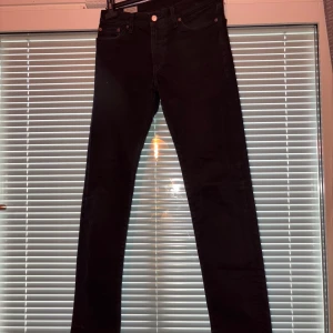 Svarta Levi's 511 jeans slim fit - Säljer ett par svarta Levi's 511 jeans i slim fit-modell. Klassisk femficksdesign, normalhög midja och raka ben. Jeansen är tillverkade i mjukt denimtyg och har den ikoniska Levi's-lappen bak samt röd logotag på fickan.