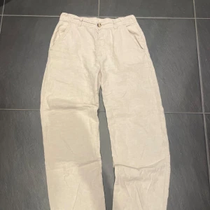 Beige linnebyxor med rak passform - Snygga och luftiga beige linnebyxor med rak passform. Perfekta för varma dagar och ger en chill vibe till din outfit. Byxorna har en enkel design och är gjorda i ett tunt, svalt linnematerial.