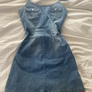Jeansklänning från edc by Esprit - Snygg jeansklänning med smala axelband från edc by Esprit. Klänningen har två bröstfickor med knappar, markerad midja och dragkedja i ryggen. Perfekt för sommaren!