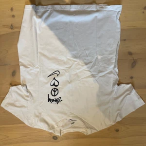 Vit Nike x Stussy t-shirt med grafiskt tryck - Säljer en vit t-shirt från Nike x Stussy i loose fit med svart grafiskt tryck framtill. Trycket består av en swoosh, hjärta, peace-märke och graffiti-liknande text. Klassisk rund hals och korta ärmar. Perfekt för dig som gillar streetstyle och snygga prints.