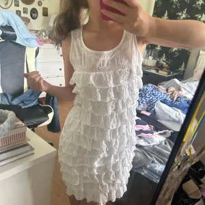 Vit volangklänning med broderi - Superfin vit kortklänning med broderade detaljer upptill och flera lager volanger. Så fin till sommaren eller som studentklänning