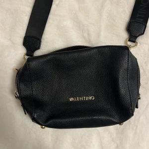 Svart axelväska från Valentino - Säljer min älskade axelväska från Valentino! Köpt 2023, den är i nyskick basically, använde den en hel sommar sen enbart ett fåtal gånger🎊 Den har inga defekter, ingen dustbag tillkommer tyvärr😫 Den har två innerfickor, en med en dragkedja, sen en korthållare på baksidan😍 Axelbandet är justerbart. Köpt för 2000kr 