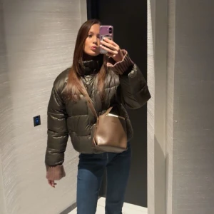 Grön pufferjacka - Säljer en snygg svart pufferjacka med hög krage och dragkedja. Jackan har en normal passform och är perfekt för kyligare dagar. Den är stilren och lätt att matcha med olika outfits. Från carin wester 😍