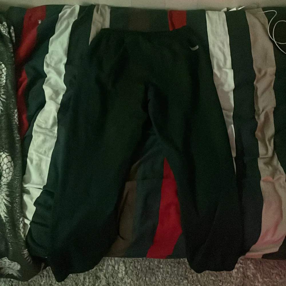 Snygga svarta byxor från Emporio Armani EA7 med en diskret logga på sidan. Perfekta för en stilren look. Byxorna har en dragkedja och är tillverkade i ett bekvämt material.. Farkut & Housut.