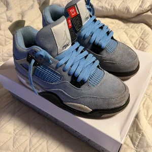Air Jordan 4 Retro ”unc blue” - Säljer ett par Air Jordan 4 Retro i en snygg kombination av blått och svart. Skorna har en stilren design med ljusblå snörning och detaljer i mocka. Pris kan diskuteras 