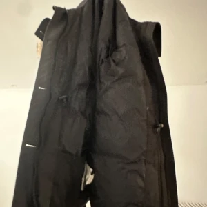 Svart parkajacka med pälsdetalj från Canada Goose - Säljer en svart parkajacka från Canada Goose med en snygg pälsdetalj på huvan. Jackan har en klassisk design med dragkedja och knappar framtill. Perfekt för kalla dagar.Allt e perfekt med den pris kan diskuteras och den är äkta och i bra skick