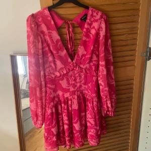 Rosa mönstrad klänning - Säljer en super fin rosa klänning som är perfekt till sommaren . Klänningen har en v-ringad design, långa ärmar och är även öppen i ryggen. Använd 1 gång 