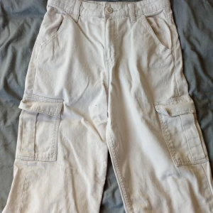 Beige cargobyxor från H&M Divided - Säljer ett par beige cargobyxor från H&M Divided. Byxorna har flera praktiska fickor och en dragkedja framtill. Perfekta för en avslappnad stil med en loose passform.