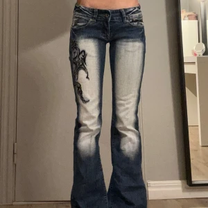 Blå bootcut jeans från Crazy Age - Supersnygga blå jeans från Crazy Age med broderad detalj. De har en bootcut-stil och är väldigt lågmidjade. Jag är 170cm lång💕 skriv om ni vill ha fler mått, pris kan diskuteras!