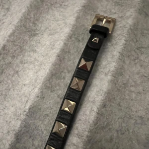 Valentino Garvani armband - Snyggt svart armband i skinn från Valentino Garvani  med coola silverfärgade nitar. Spännet är också i silver och har en stilren design. Box och dustbag tillkommer! Köpt för ca 3 år sedan men fortfarande i väldigt bra skick, bara lite små repor på silvret som knappt syns!