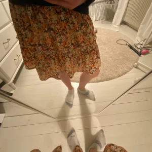 Blommig kjol - Säljer en färgglad blommig kjol med volangdetaljer. Kjolen har en kort längd och är perfekt för sommarens varma dagar. 🤩