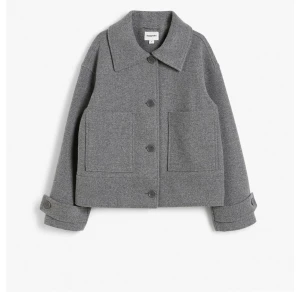 Grå kappa  - Snygg grå kappa från Kappahl med en klassisk krage och stora framfickor. Jackan har långa ärmar med knappar vid ärmsluten och en rak passform. Perfekt nu till våren!!