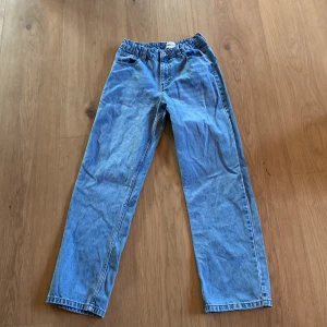 Blå jeansbyxor från M.D by denim dpt - Snygga blå jeansbyxor med elastisk midja från M.D by denim dpt. Byxorna har en klassisk rak passform och två bakfickor. Perfekta för en avslappnad stil. Baggy jeans