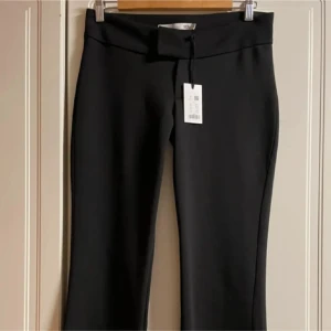 Svarta byxor med bootcut - Snygga svarta byxor med bootcut-stil och hög midja. Perfekta för en stilren look. Byxorna har en enkel design utan mönster och är tillverkade i ett mjukt material som ger en bekväm passform.