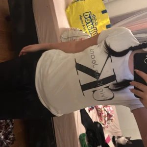 Vit t-shirt från Calvin Klein - Säljer en vit t-shirt från Calvin Klein med det klassiska CK-logotypen tryckt i svart på framsidan. T-shirten har en normal passform och korta ärmar. Perfekt för en avslappnad stil.