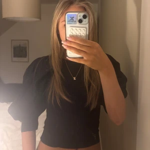 Svart blus från Lindex  - Snygg svart blus från Lindex med puffiga ärmar och rund halsringning. Perfekt för en stilren look. Passar bra till både jeans och kjol.