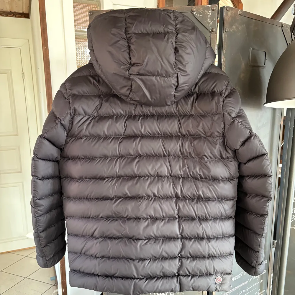 Säljer en snygg svart dunjacka från Colmar. Jackan har en avtagbar huva och praktiska dragkedjor på fickorna. Perfekt för kyliga dagar med sin vadderade design och stilrena look. Passar både till vardags och mer uppklädda tillfällen. Jackan har även 6 fickor på framsidan och en stor innerficka! Fickorna få bröstet har fleece i fickorna som håller dina händer varma!. Takit.