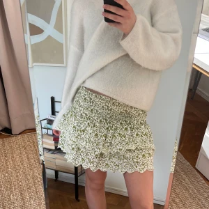 Grön blommig kjol med volang - Charmig kortkjol i grönt och vitt med blommigt mönster och volangdetaljer. Perfekt för en somrig look med sin luftiga design och elastiska midja.