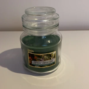 Grön doftljus i glasburk från Inicio - Säljer ett grönt doftljus i glasburk från Inicio med doften 'Magical Winter Eve'. Perfekt för att skapa en mysig vinterstämning hemma. Burken har ett lock för att bevara doften när ljuset inte används.