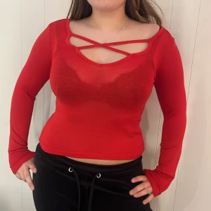 Röd långärmad topp med korsdetalj - Snygg röd långärmad topp med en unik korsdetalj vid halsringningen. Perfekt för att ge en extra touch till din outfit. Toppen har en tight passform och är tillverkad i ett mjukt och stretchigt material. Gjord i XS men passar bra på allt från XXS till M. Över M blir lite tajt💓