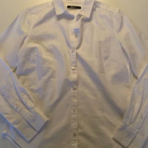 Vit skjorta från Gina Tricot - Säljer en klassisk vit skjorta från Gina Tricot. Skjortan har långa ärmar och knappar framtill. Perfekt för en stilren look.