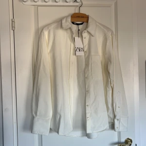 Vit skjorta från Zara - Snygg vit skjorta från Zara i en klassisk design. Skjortan har långa ärmar och knappar framtill. Perfekt för en stilren look.