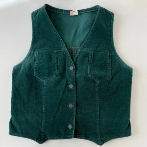 Cool Vintage Manchesterväst - Vintage manchesterväst i superfin grön färg. Perfekt för att lägga till en touch av stil till din outfit. Den har en justerbar rem med knappar på baksidan för en bättre passform. Strl 38/40.
