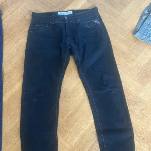 Svarta jeansbyxor från Replay - Snygga svarta jeansbyxor från Replay med klassisk femficksdesign och knappgylf. Byxorna har en stilren look med diskreta sömmar och passar perfekt för en avslappnad stil.