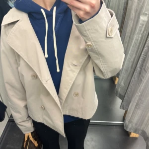 Beige trenchcoat - Säljer en Snygg kort trenchcoat från lager 157. Lite ”trenchcoat buttoned to the top” vibe🤪. Jackan har långa ärmar och en klassisk design som funkar till många outfits. Priset kan diskuteras💕🥰