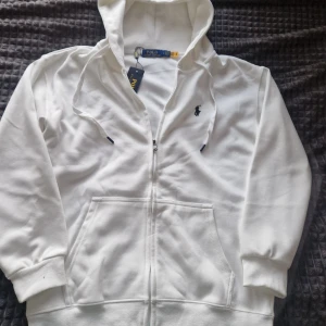 Vit hoodie från Polo Ralph Lauren - Säljer en helt ny vit hoodie från Polo Ralph Lauren. Den har en dragkedja framtill och en klassisk broderad logga på bröstet. Fick i födelsedagspresent men den var för liten. Passar mer som M. Hör av dig vid intresse! 