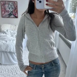 Grå hoodie från Soft Goat - Mysig grå hoodie från Soft Goat i kashmir. Den har dragkedja framtill och en praktisk huva. Perfekt för kyliga dagar med sin mjuka och bekväma passform. 🐐