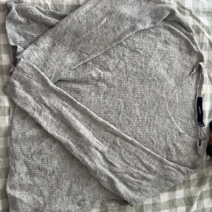 Grå ribbad tröja - Säljer en stilren grå ribbad tröja med långärmad design. Perfekt för en avslappnad look. Tröjan har en mjuk och bekväm passform.